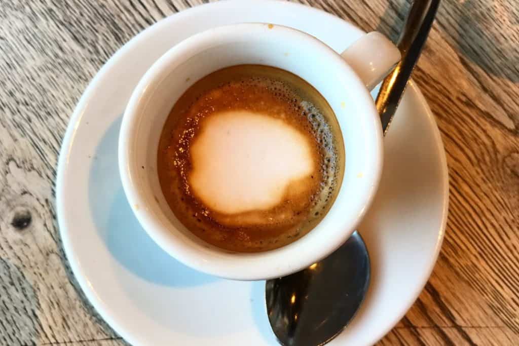 Caffè Macchiato brun med vitt skum i kopp