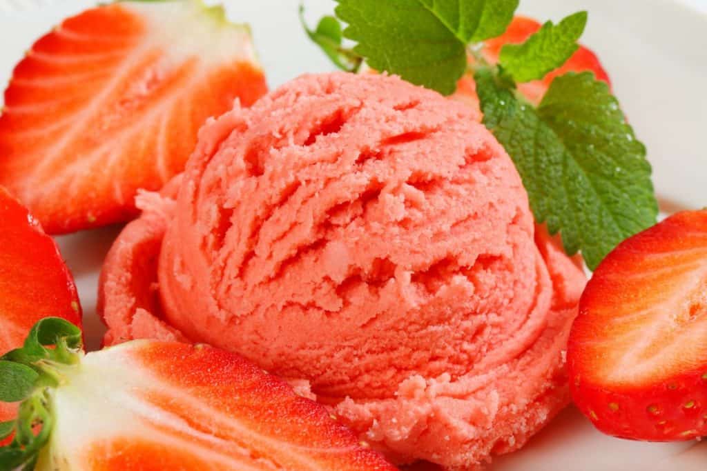 Sherbet röd glass med jordgubbar bredvid